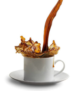 Coffee being poured from a source outside of "view" into a cup, with coffee splashed over the sides