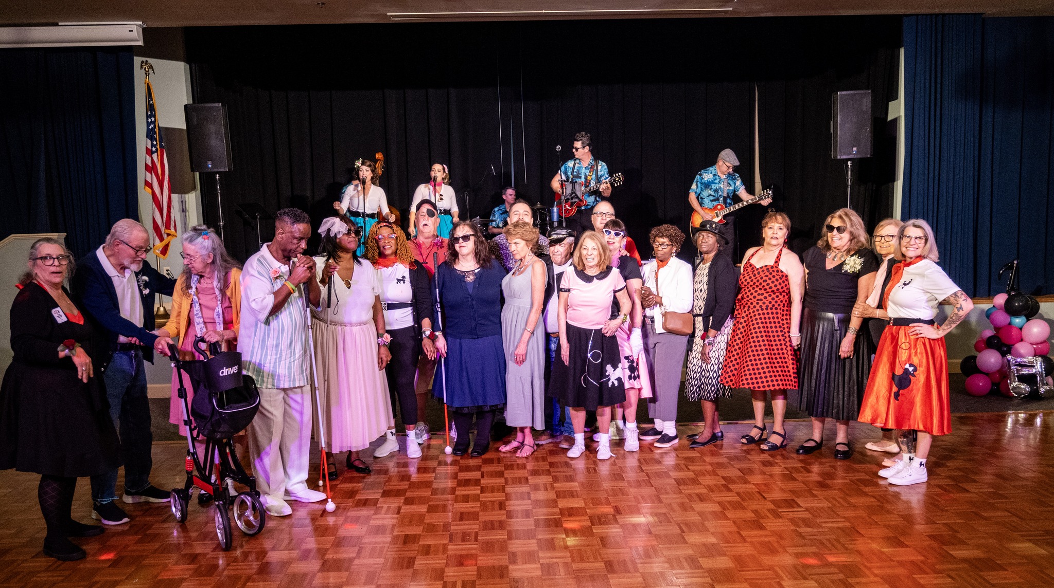 New Vision clients gather around the stage, in front of the band for a group photo at the Senior Citizens Prom in Mount Dora.
