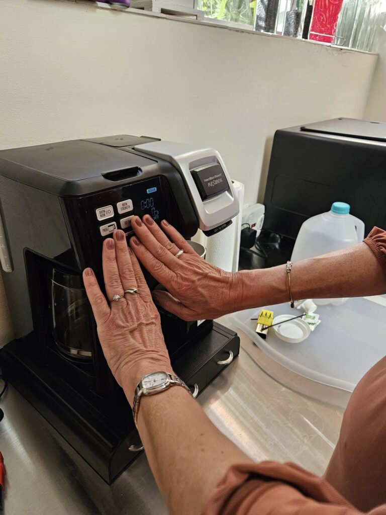 Two hands feel buttons on a coffee maker