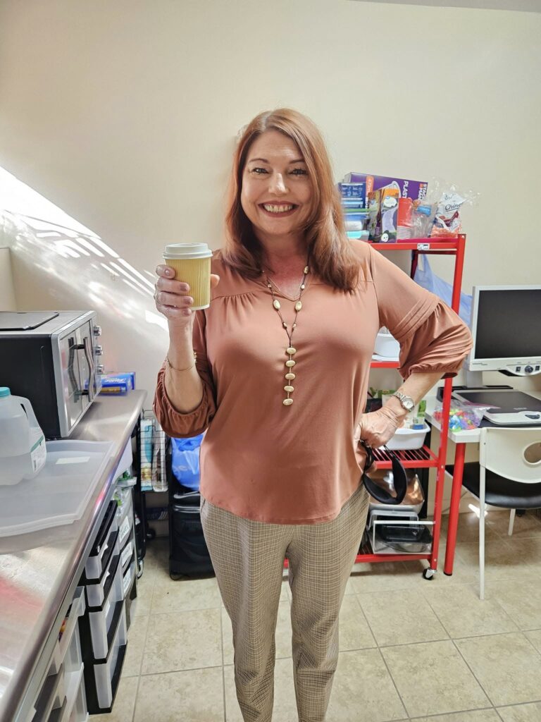 Woman smiling holding a cup of coffee