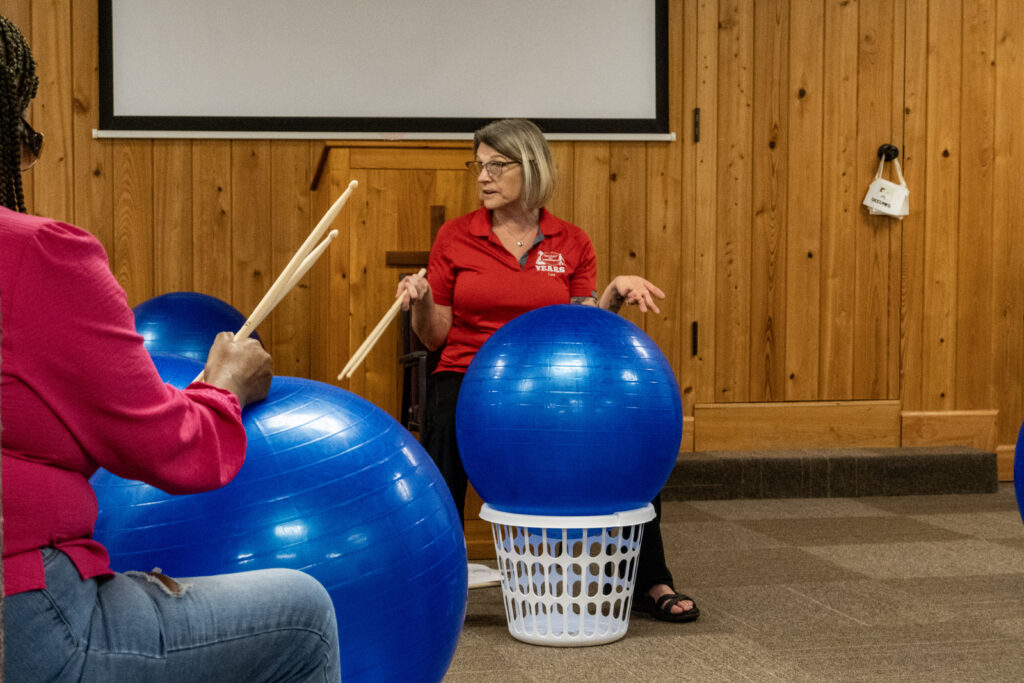 New Vision's Lisa sits at the front of the room behind her bright blue exercise ball and explains some of the benefits of cardio drumming to the group before getting started.