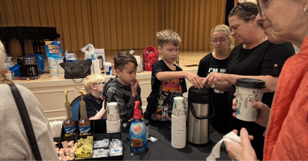 One of the kids from the New Vision children's program pushes down on the top of the coffee carafe to serve patrons at the Low Vision Expo in The Villages.
