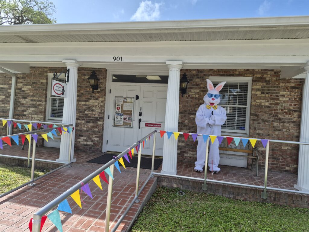 Bob, the Easter bunny's blind brother, stands on the porch of New Vision's office. The railings are decorated with small colorful pennants.