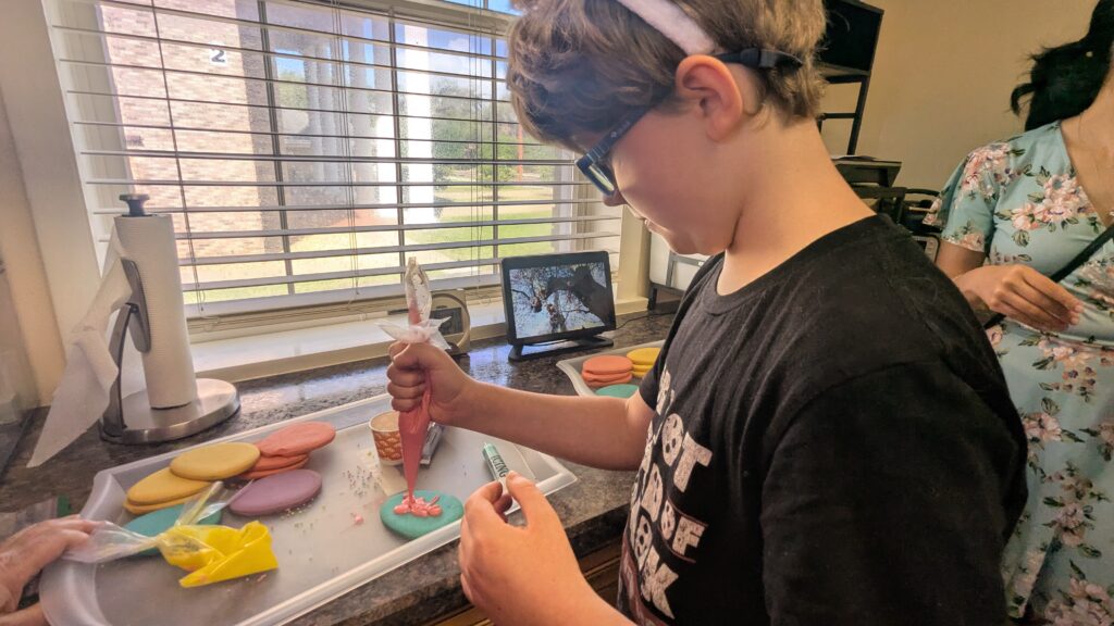 One of the kids ices a blue egg-shaped cookie with pink icing during the Sensational Egg Hunt.