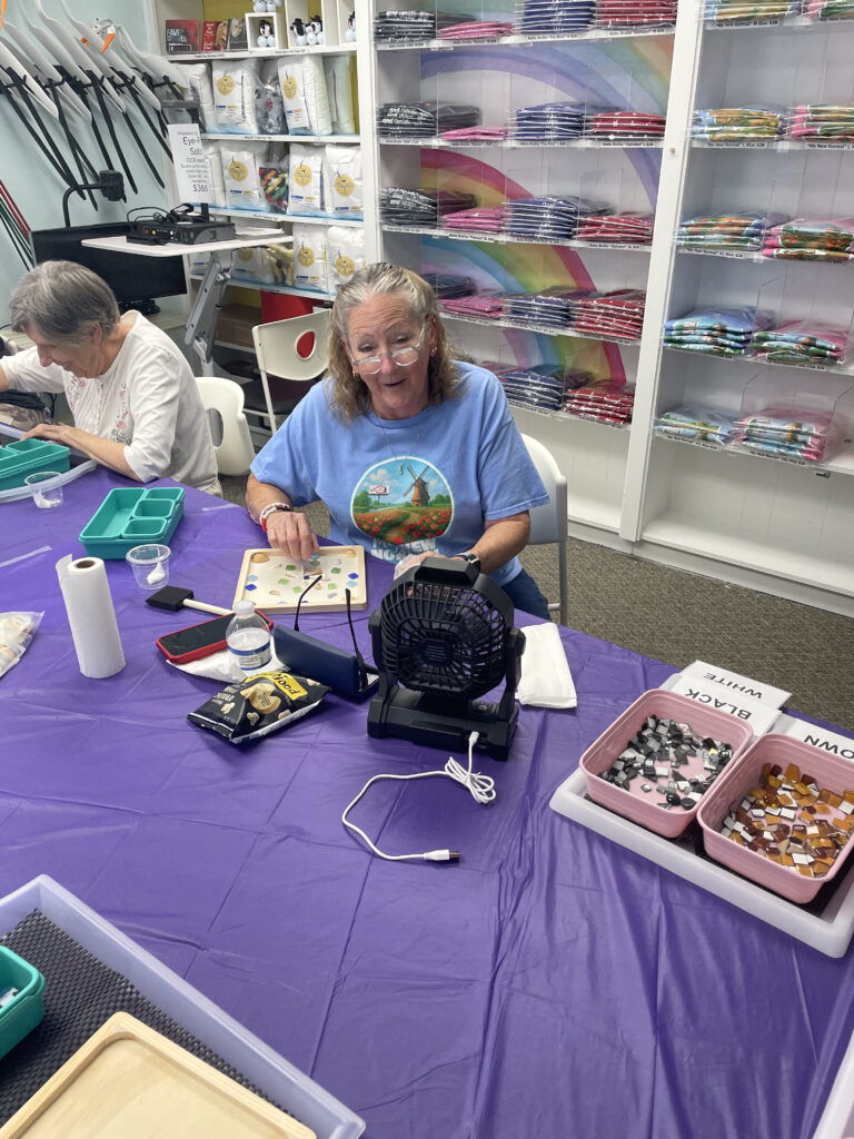New Vision's Jojo works on her mosaic, gluing tiles on the wooden frame.
