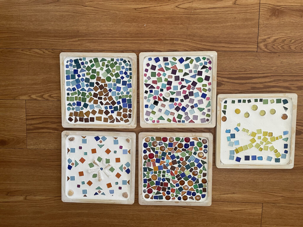 Five finished mosaic pieces features various colors and designs.
