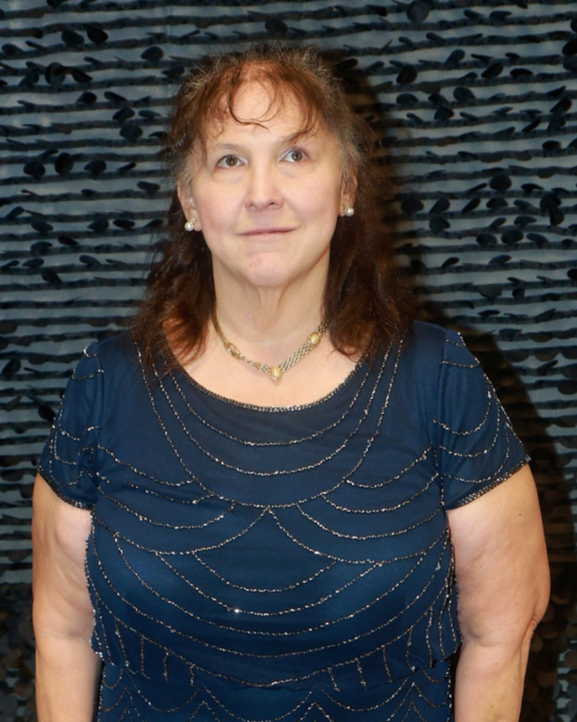 New Vision's Christy stands in front of a striped background. 