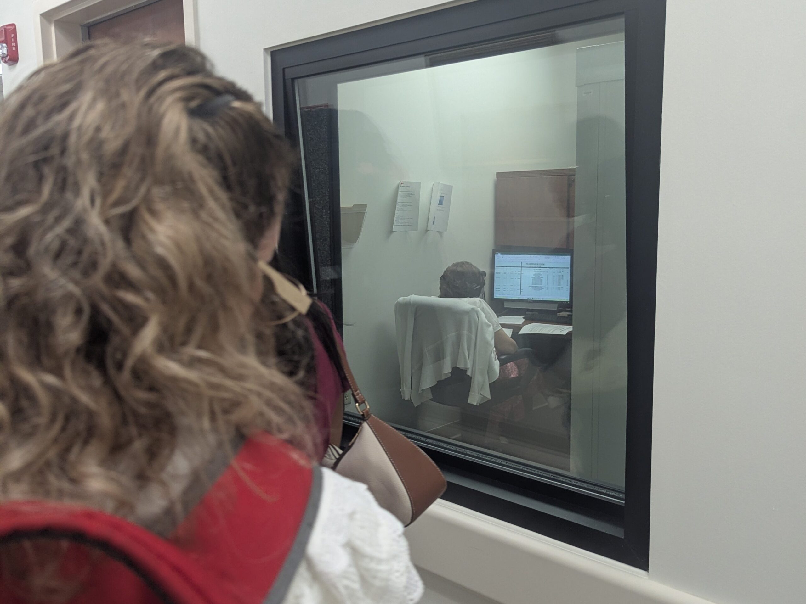 A visitor from New Vision for Independence peaks into one of the recording booths at the Talking Library in Daytona.